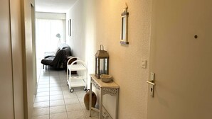 A hallway with a bed, a white cart, a lantern, and a wall-mounted mirror.