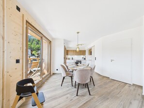 A modern interior with a dining area, kitchen, and large sliding glass doors leading to an outdoor space.