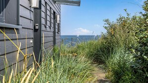 A pathway leading to a building with a view of the sea and sailboats.