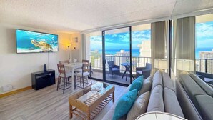 A modern living room with a balcony, a flat-screen TV, a dining area, and a sofa.