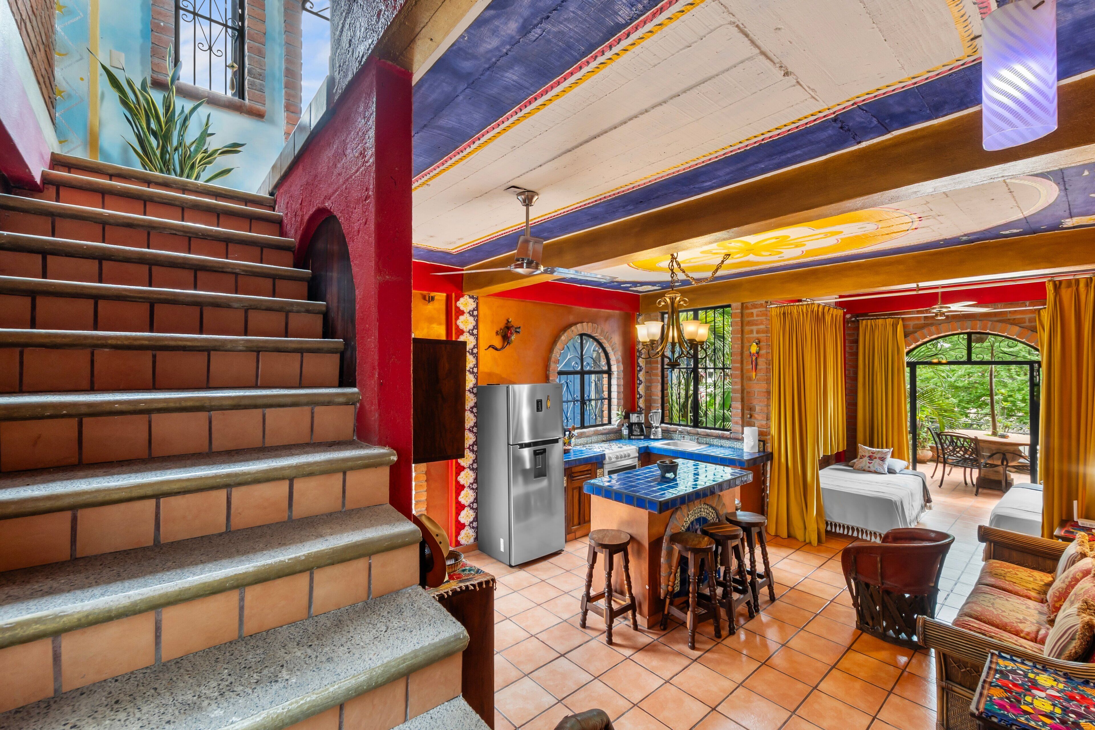 Una cocina con una isla central, un refrigerador y un comedor con mesa y sillas.