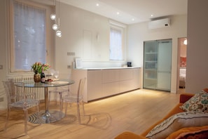A modern kitchen with a glass dining table, clear chairs, and a central island. - Independent house- Heart of Rome (Roma)