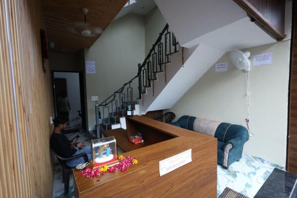 A reception desk with a sign, a staircase, and a sofa.
