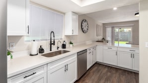 A modern kitchen with white cabinetry, a stainless steel sink, and a dishwasher.