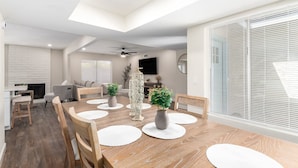 A modern dining area with a wooden table, white placemats, and chairs.
