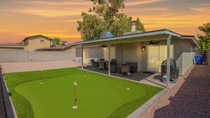 A modern house with a covered patio, a well-maintained lawn, and a clear view of the sunset.