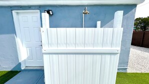 Ein weißer Zierzaun vor einem Haus mit blauer Außenwand und einer weißen Tür.
