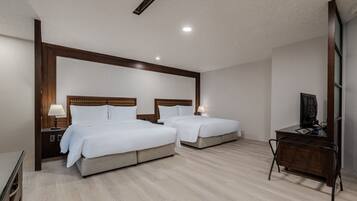 A hotel room with two beds, a desk, and a TV.