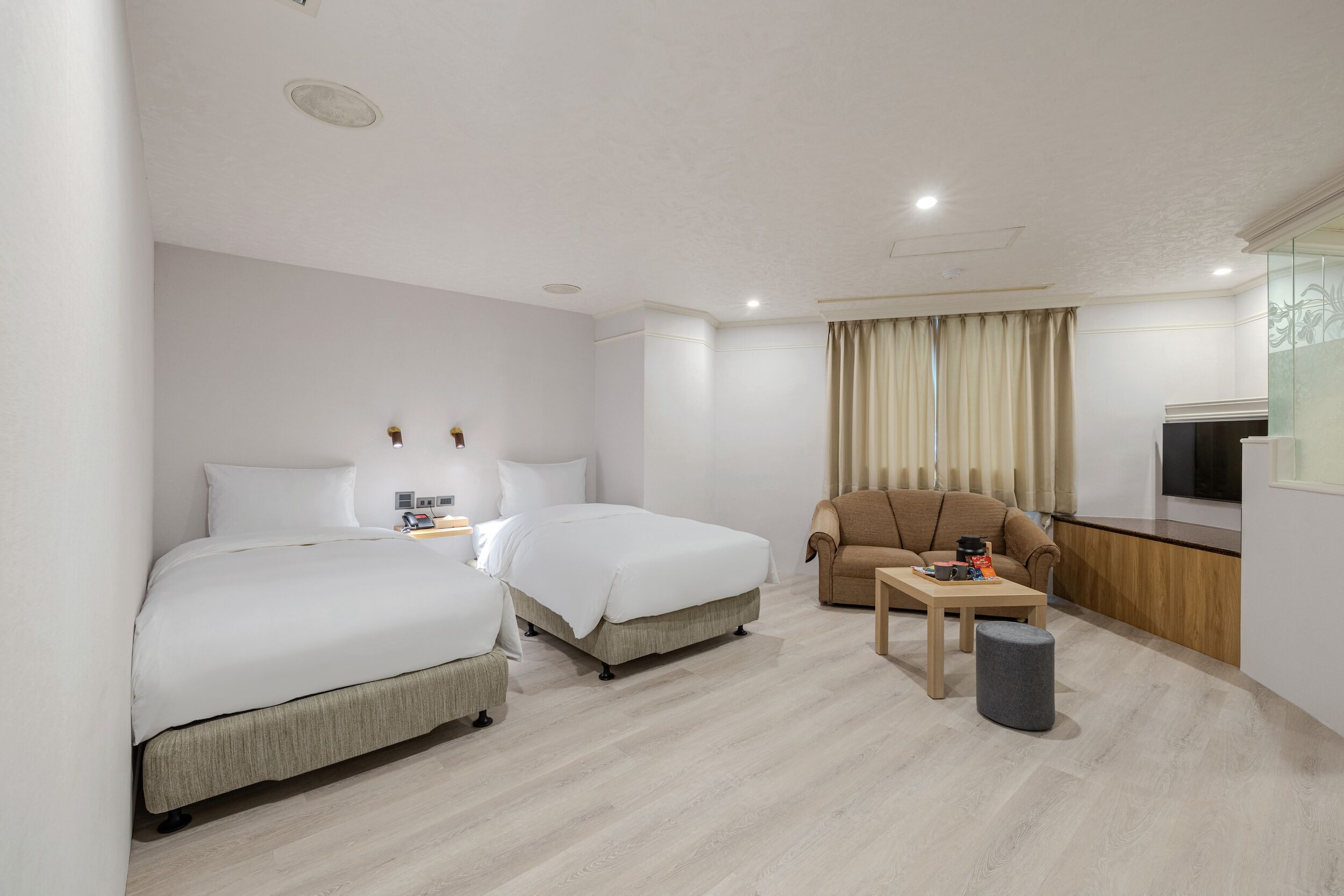 Una habitación de hotel moderna con una cama, un sofá, una mesita y un televisor.