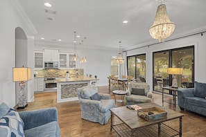 A spacious living room with a large sofa, a coffee table, and a dining area with a chandelier. - 4 Bedroom Townhome - Villa Lago at Sandestin Golf & Beach Resort! (Miramar Beach)