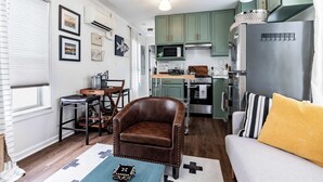 A compact living space with a dining area, a sofa, a coffee table, and a kitchenette.