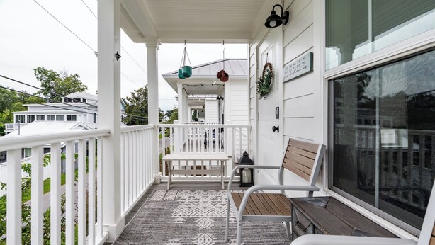 A covered porch with a patterned rug, a bench, and a table.