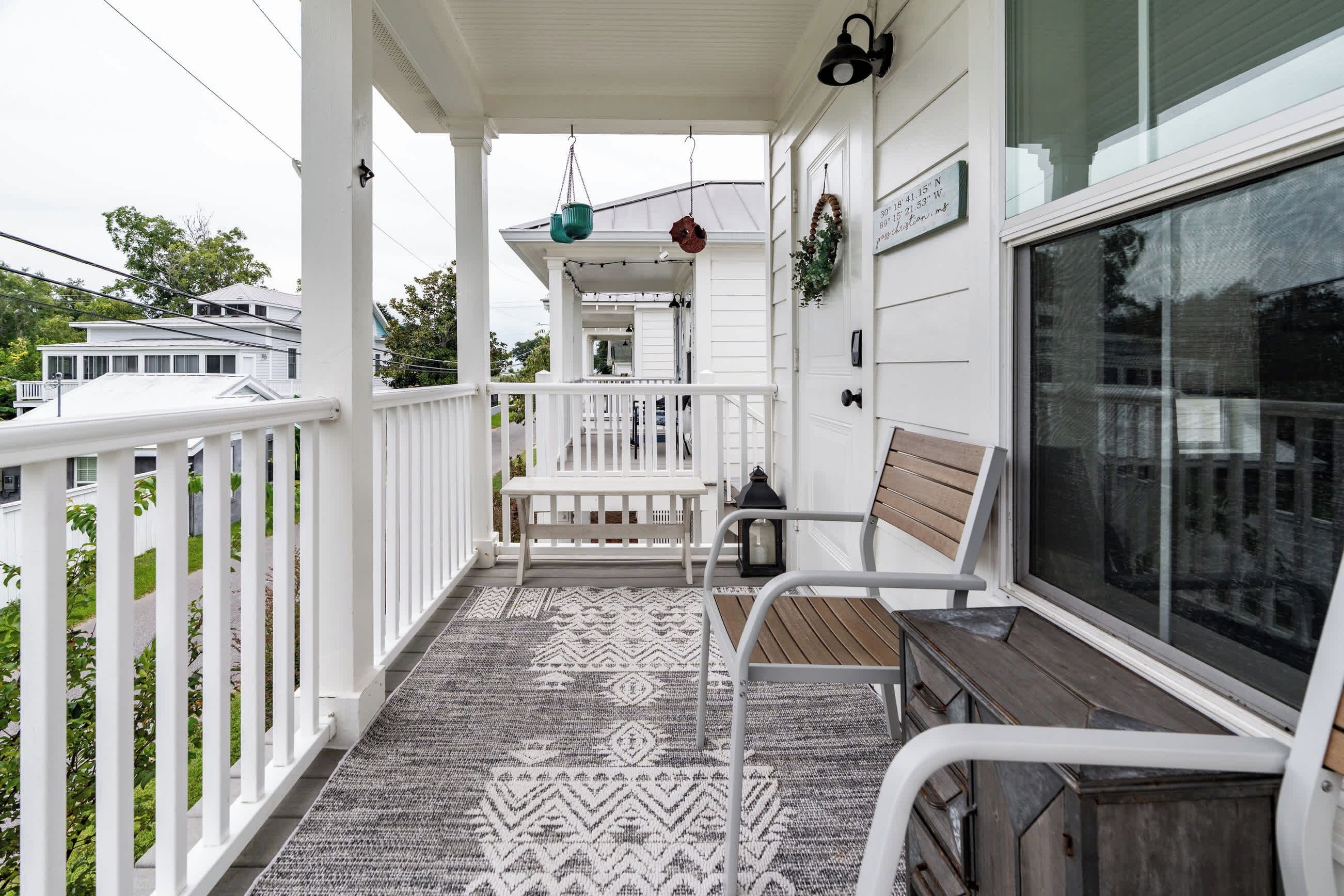 A covered porch with a patterned rug, a bench, and a table.