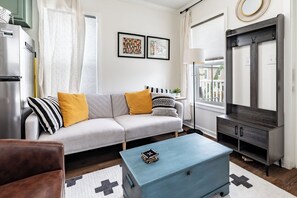 A modern living room with a sofa, coffee table, and a TV stand.