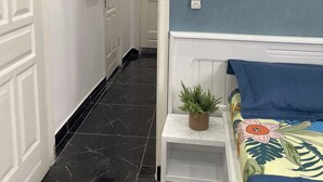 Un couloir avec un lit, une petite plante et une porte.