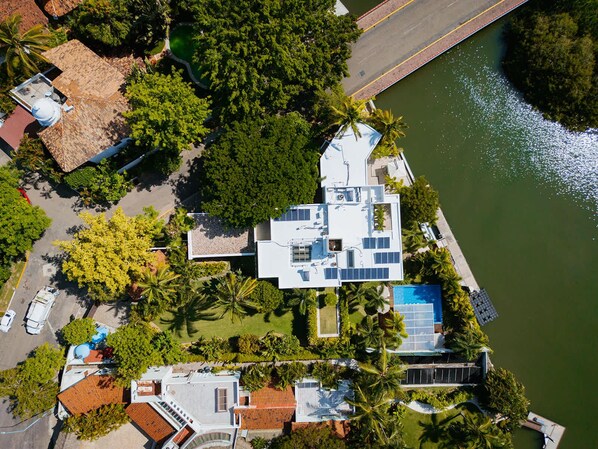 Vista aérea de una casa moderna con piscina, rodeada de exuberante vegetación y un río.