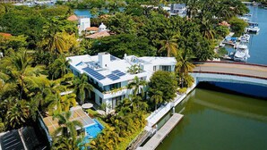 Une maison moderne dotée de panneaux solaires, d’une piscine et d’un quai situé près d’une marina.