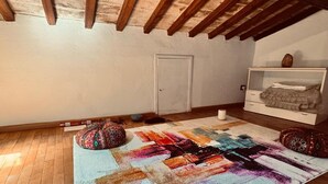 A room with a wooden ceiling, a door, a white dresser, a colorful rug, and a small table with a lamp. - Lovely apartment for 4 people with WIFI, A/C and panoramic view (Cortona)