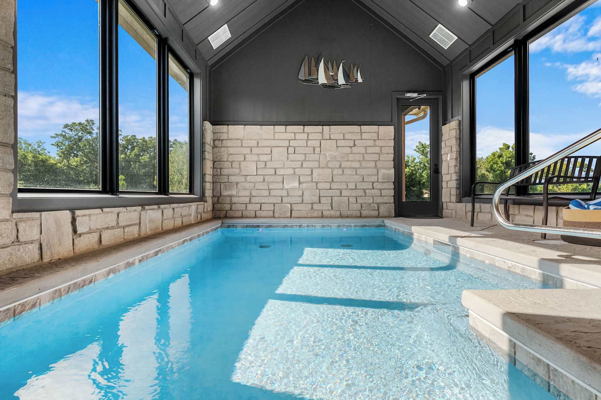 An indoor swimming pool with stone walls and large windows.