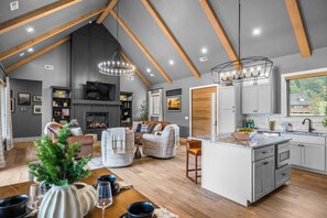 A spacious living area with a fireplace, seating, and a kitchen with a large island. - Luxury Cabin, Sleeps 12・Pool, Hot Tub + Family Fun (Sevierville)