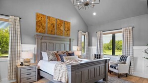 A bedroom with a large bed, bedside tables, a chair, and a view of the outdoors.