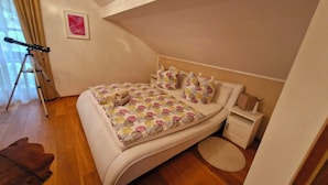Une chambre à coucher avec un lit, des oreillers, une table de chevet, une lampe, un trépied pour appareil photo et un tapis.