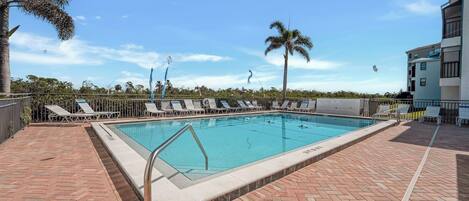 Una piscina con sillones de descanso y palmeras.