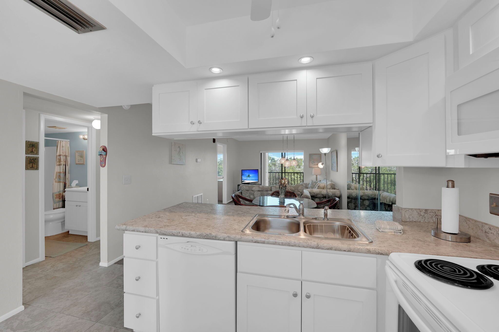 A modern kitchen with white cabinets, a granite countertop, a built-in oven, and a stainless steel sink.