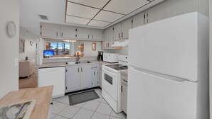 Une cuisine moderne avec des meubles blancs, un four encastré, un four à micro-ondes et un réfrigérateur.