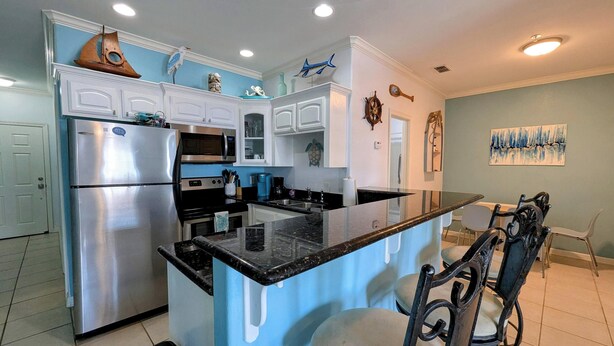 Una cocina moderna con armarios blancos, electrodomésticos de acero inoxidable y una isla central.