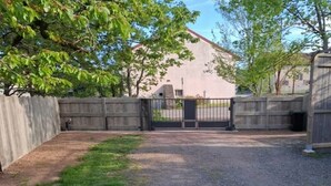 A gated driveway leading to a building with a concrete exterior and a red roof. - Maison cosie with fenced garden " DucnVosges " (Champ-le-Duc)