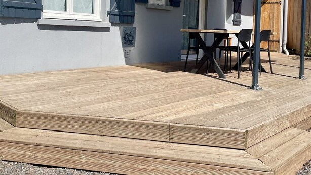 A covered patio with a wooden deck, a table, and chairs. - Maison cosie with fenced garden " DucnVosges " (Champ-le-Duc)
