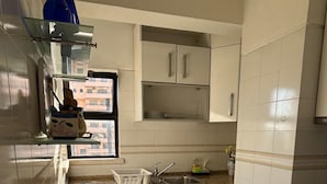 Une cuisine moderne avec des meubles blancs, des plans de travail en granit et une fenêtre qui laisse entrer la lumière naturelle.