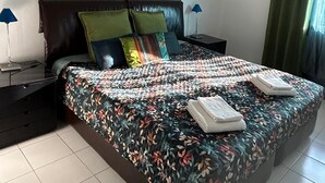 Un lit bien fait, avec une couvre-lit à motifs floraux, deux oreillers et deux serviettes pliées.