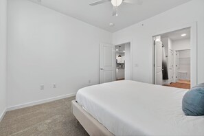 A bedroom with a large bed, a ceiling fan, and a walk-in closet.