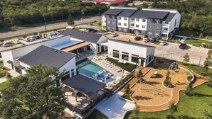 Vista aérea de un hotel con piscina, mobiliario exterior y parque infantil.