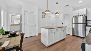 Una cocina moderna con armarios blancos, un refrigerador de acero inoxidable e iluminación colgante.