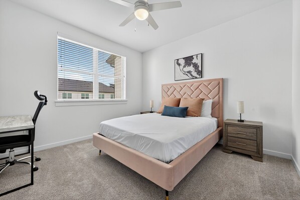 A bedroom with a bed, a desk, a chair, a nightstand, and a ceiling fan. - Spectra parks 9307 I Comfy 2 Bed 2 Bath (Austin)