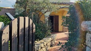 Un sendero que lleva a un edificio con fachada amarilla y puerta marrón.