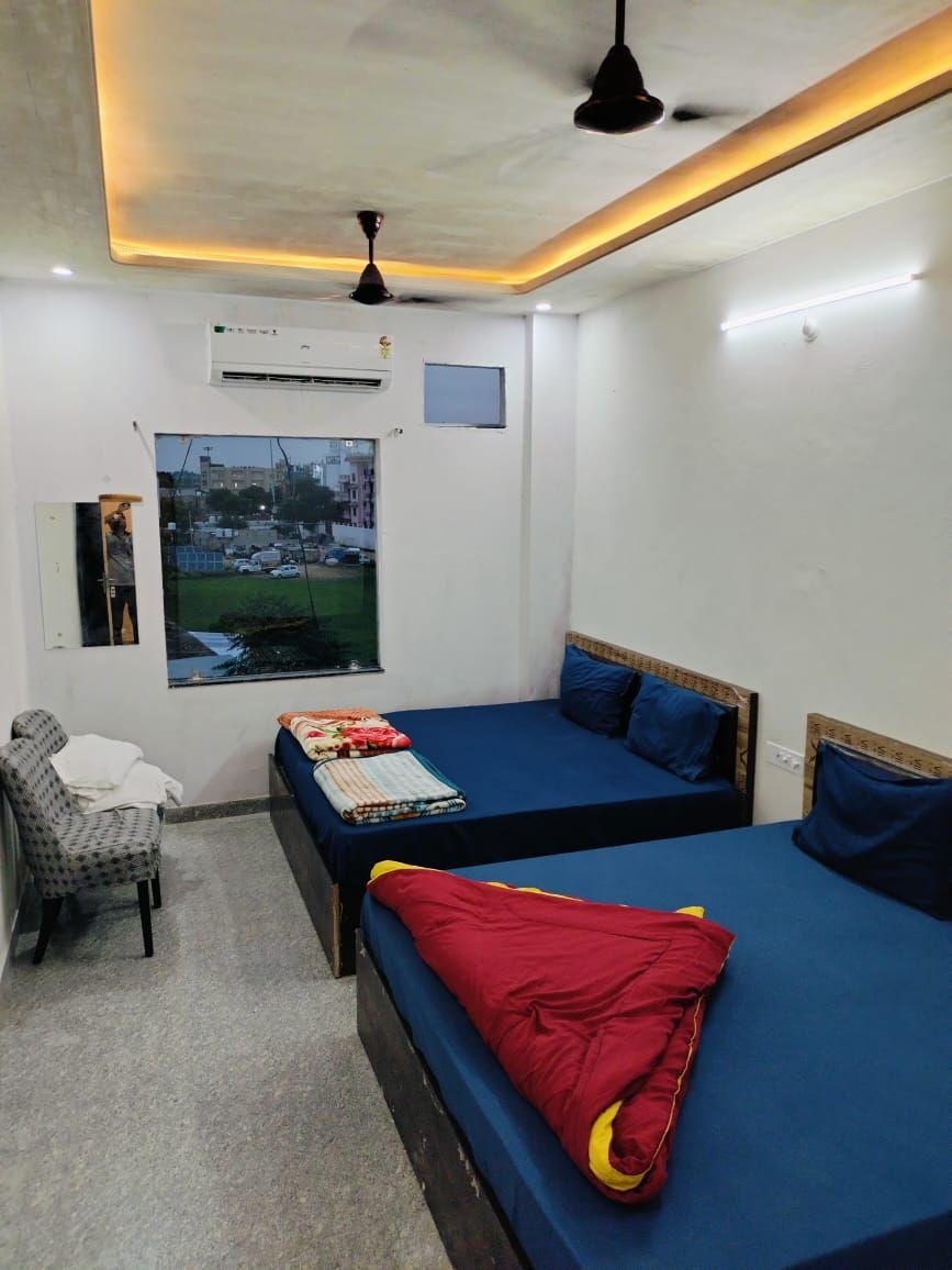 Une petite chambre propre, avec deux lits simples, une chaise et une fenêtre donnant sur la ville.