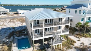 Une propriété en bord de mer, composée de plusieurs étages, dotée d’une piscine, de balcons et offrant une vue sur l’océan.