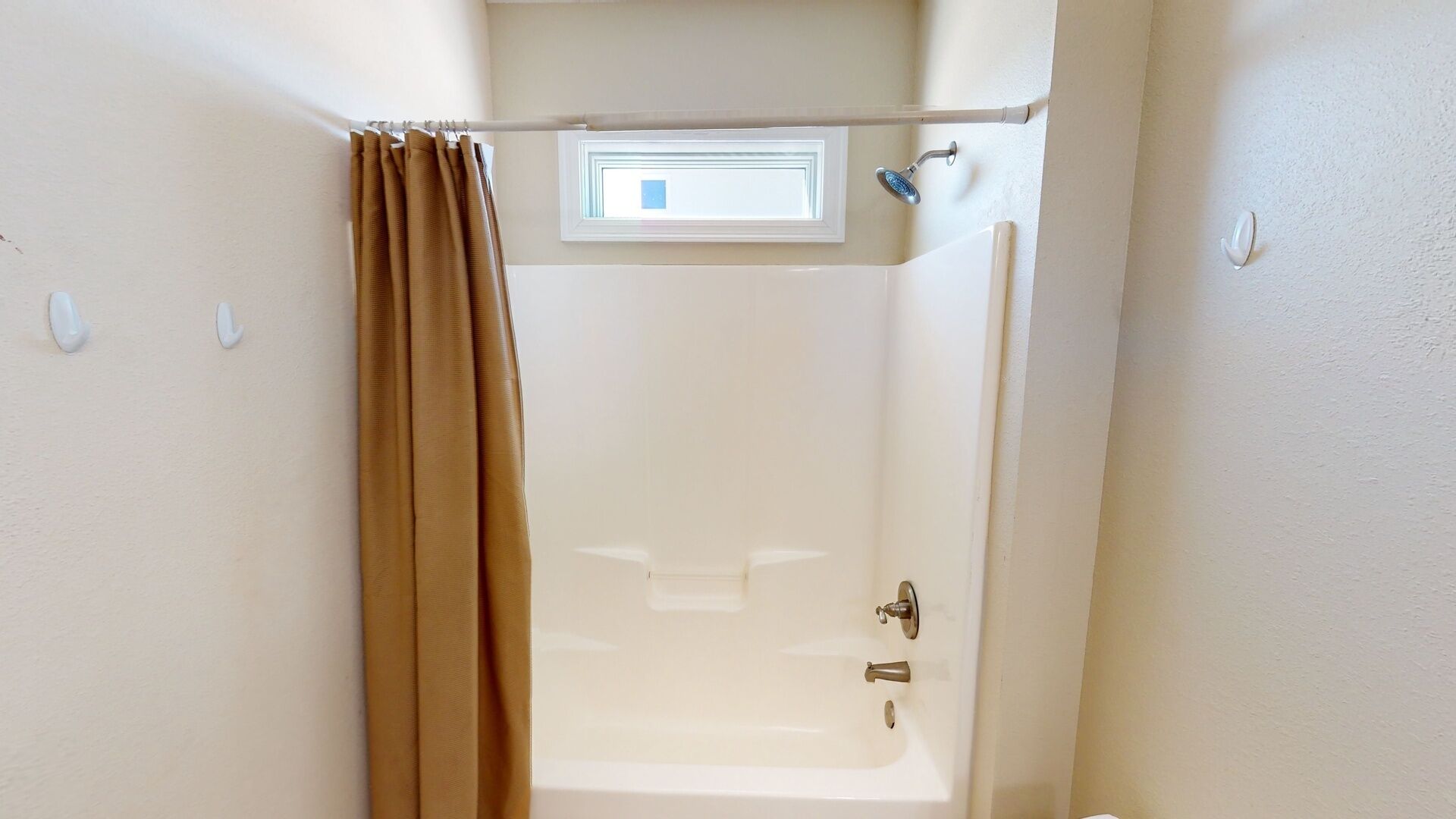 Ein Badezimmer mit Badewanne, Dusche und einem Fenster über der Dusche.