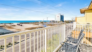 Una carretera costera con vista a la playa, un edificio de gran altura y un edificio amarillo con balcón.