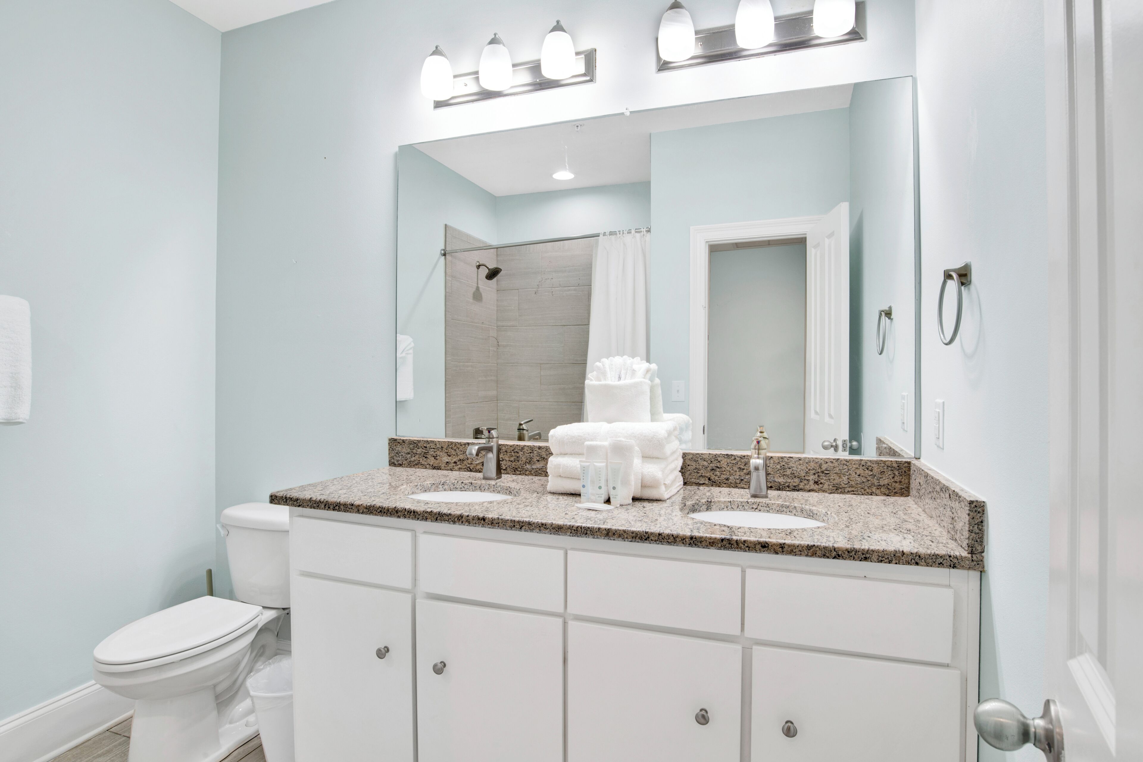 A bathroom with a double sink vanity, a shower, and a toilet.