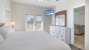 Une chambre avec un grand lit, une commode, une télévision et un balcon avec vue.