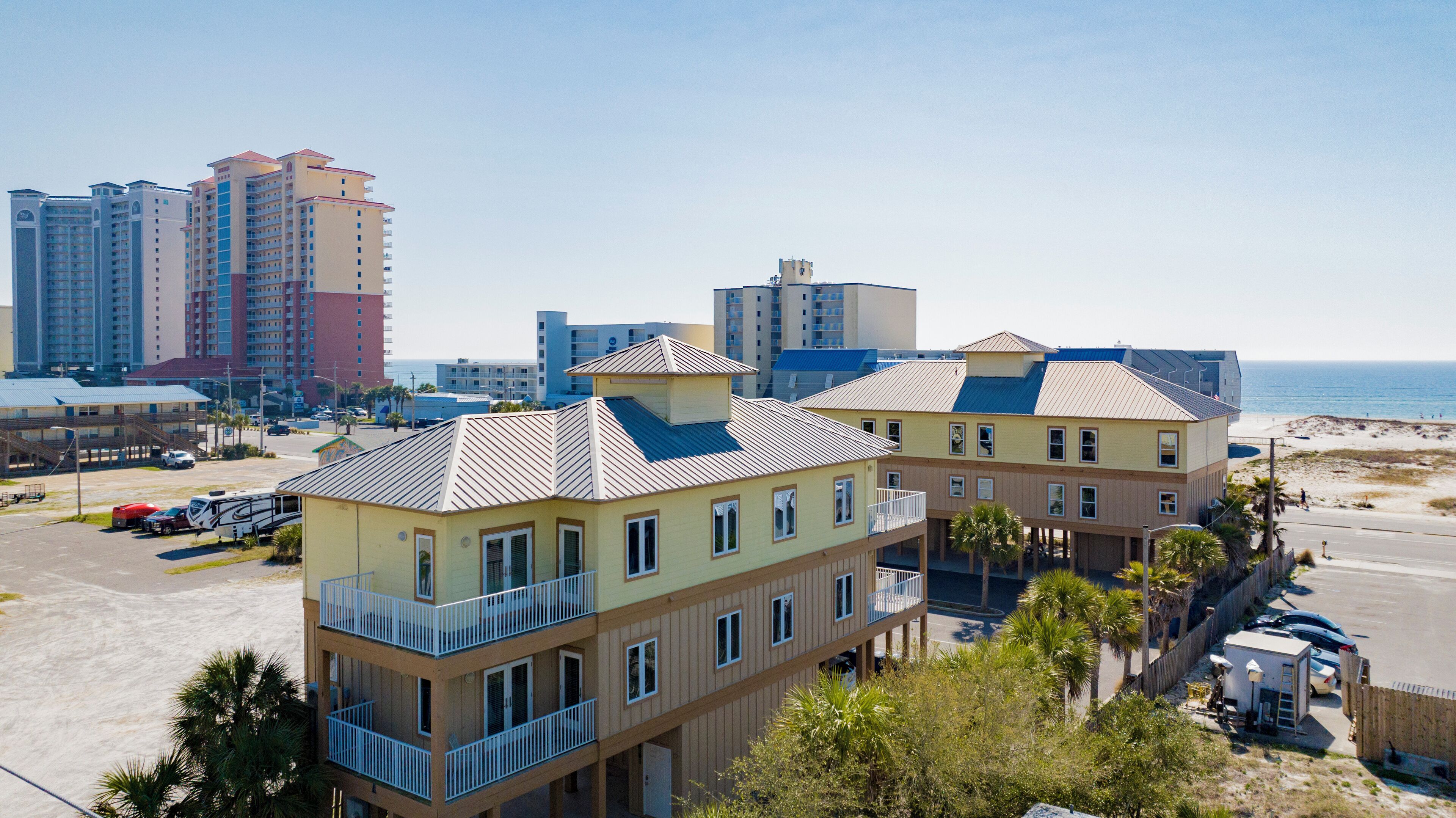 A beachfront hotel with multiple buildings, balconies, and a parking area.