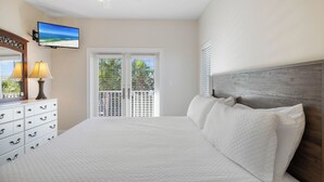 Une chambre à coucher comprenant un lit, une commode, un téléviseur et un ventilateur de plafond.