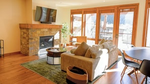 A living room with a stone fireplace, a sofa, a coffee table, and a TV mounted on the wall.
