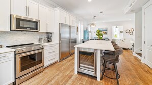 A modern kitchen with stainless steel appliances, white cabinetry, and a central island with bar stools.