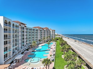 A hotel with multiple balconies, a large central pool, and a view of the ocean. - PH, Balcony, Lazy River, I-O Pools, Game Room, Spa, Beach, Luxury 2-2 Penthouse! (Galveston)